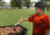 A kid cooking on a grill at the lake